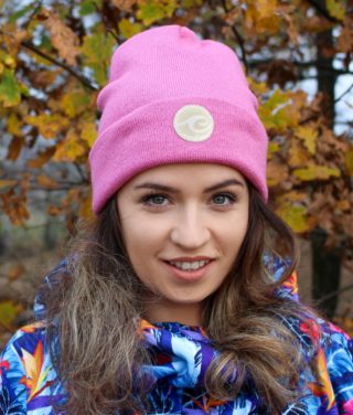 Surf beanie in dark rose colour worn by surf girl in autumn forest with leafs background.